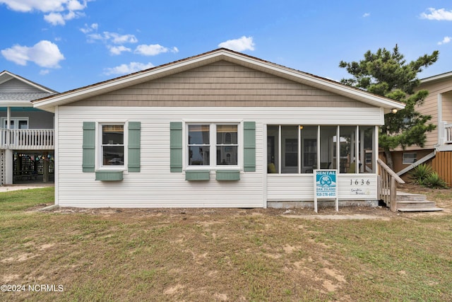 back of house featuring a lawn and a sunroom