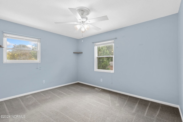 carpeted spare room featuring ceiling fan and a wealth of natural light