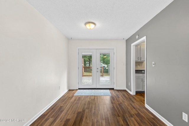 empty room with a textured ceiling, dark hardwood / wood-style floors, and french doors