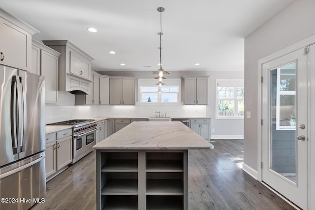 kitchen featuring hanging light fixtures, light stone counters, gray cabinets, a kitchen island, and appliances with stainless steel finishes