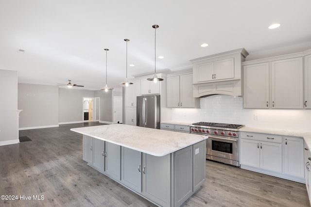 kitchen with hardwood / wood-style floors, stainless steel appliances, a kitchen island, and hanging light fixtures