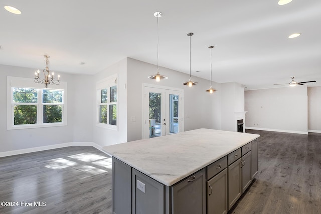 kitchen with gray cabinetry, hanging light fixtures, dark hardwood / wood-style floors, a kitchen island, and ceiling fan with notable chandelier