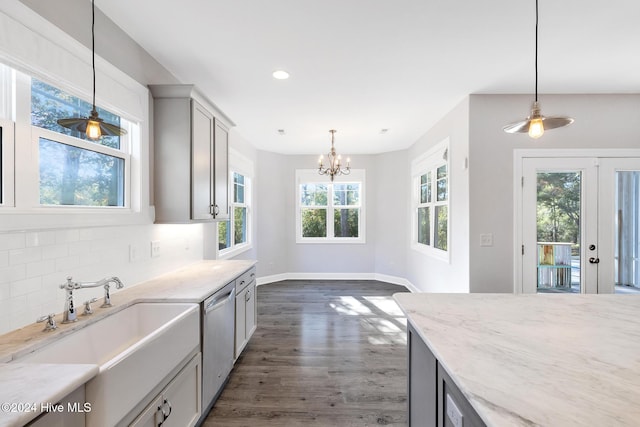 kitchen with stainless steel dishwasher, backsplash, hanging light fixtures, and dark wood-type flooring