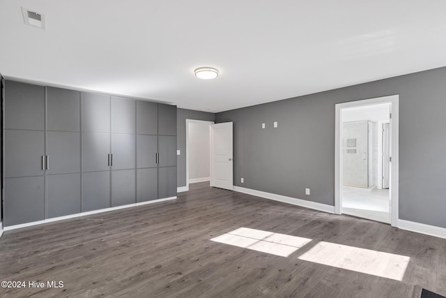 unfurnished bedroom featuring ensuite bath, a closet, and wood-type flooring