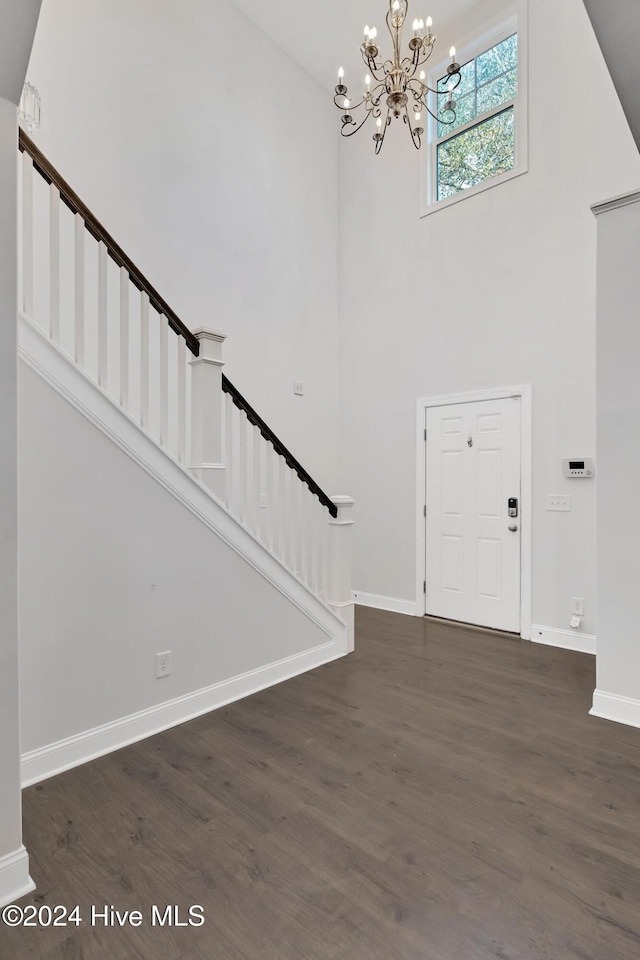 entryway featuring a towering ceiling, dark hardwood / wood-style floors, and a notable chandelier