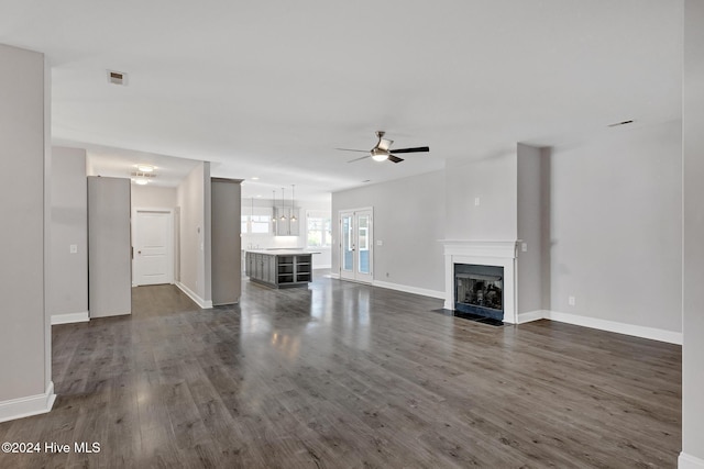 unfurnished living room with ceiling fan and dark wood-type flooring