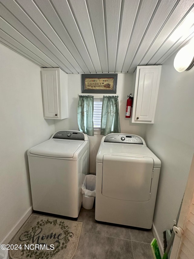 laundry area with washer and clothes dryer, cabinets, and dark tile patterned floors