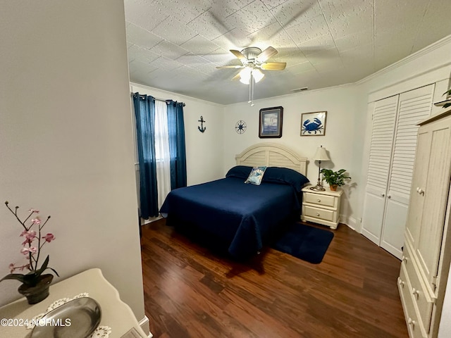 bedroom with crown molding, dark hardwood / wood-style flooring, ceiling fan, and a closet