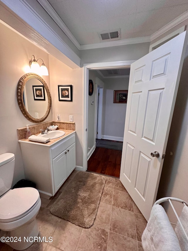 bathroom with ornamental molding, vanity, and toilet