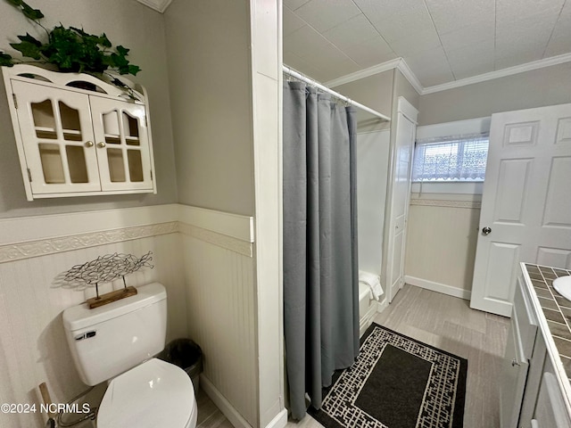 bathroom featuring toilet, hardwood / wood-style flooring, ornamental molding, vanity, and curtained shower