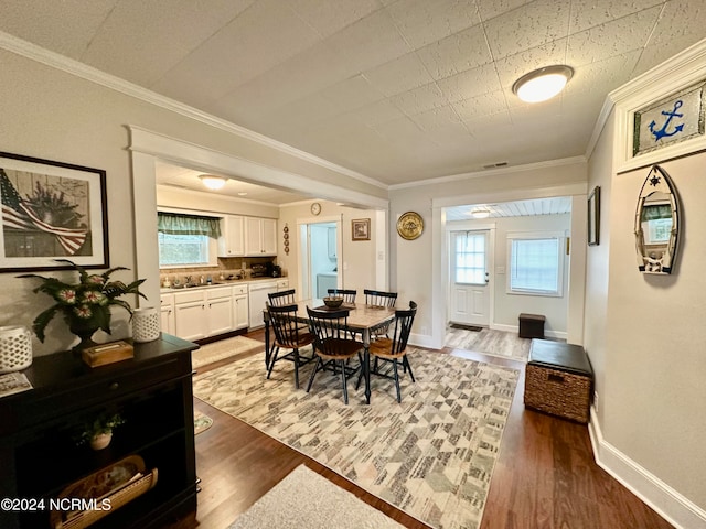 dining space with crown molding, dark hardwood / wood-style flooring, sink, and plenty of natural light