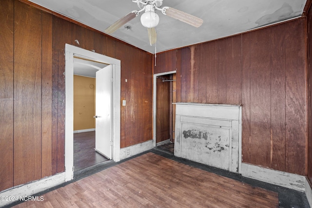 unfurnished living room with wood walls, ceiling fan, and dark hardwood / wood-style floors