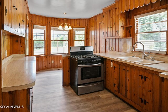 kitchen featuring light hardwood / wood-style floors, pendant lighting, stainless steel gas range, an inviting chandelier, and sink