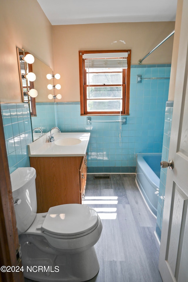 full bathroom with tile walls,  shower combination, hardwood / wood-style floors, vanity, and toilet