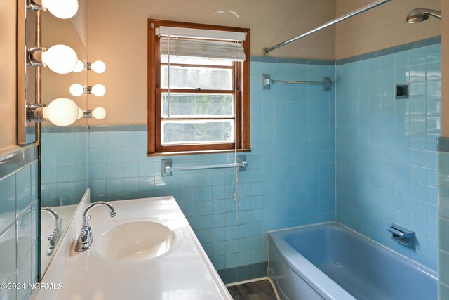 bathroom featuring tile walls, tiled shower / bath combo, and vanity