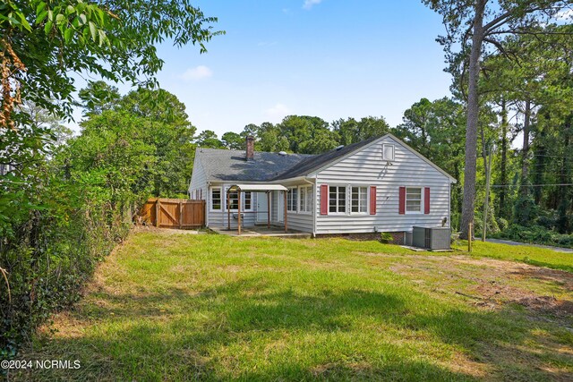 back of property with central AC unit, a patio area, and a yard