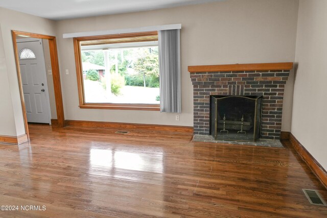 unfurnished living room featuring a brick fireplace and hardwood / wood-style flooring