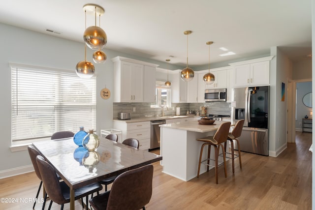 kitchen with pendant lighting, stainless steel appliances, plenty of natural light, and white cabinets