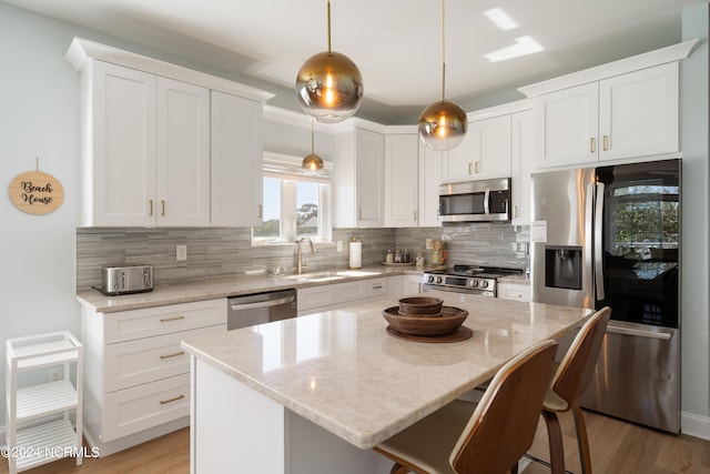 kitchen with decorative backsplash, stainless steel appliances, a center island, decorative light fixtures, and sink