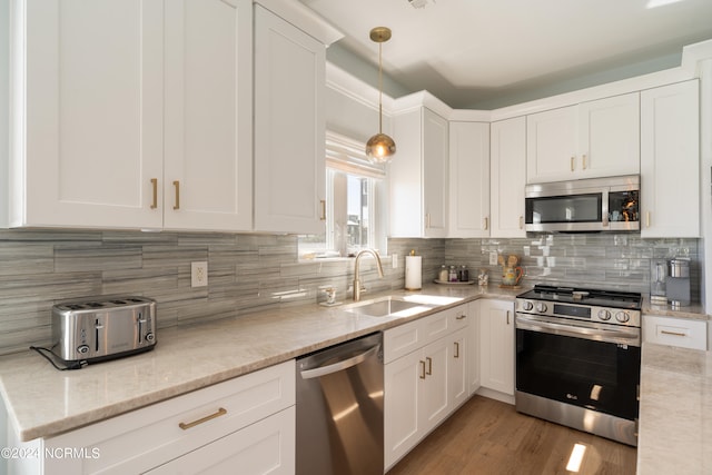 kitchen with pendant lighting, stainless steel appliances, sink, and white cabinets