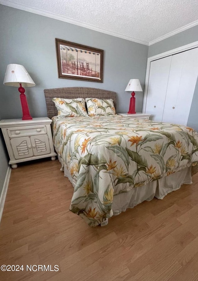 bedroom featuring crown molding, a closet, wood-type flooring, and a textured ceiling