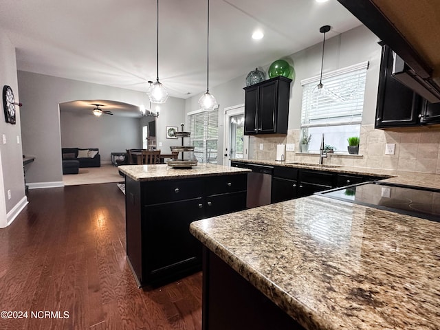 kitchen with sink, hanging light fixtures, a center island, stainless steel dishwasher, and dark wood-type flooring