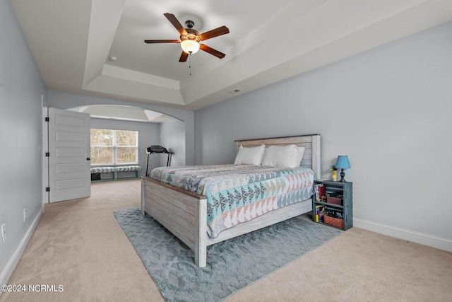 carpeted bedroom featuring ceiling fan and a tray ceiling