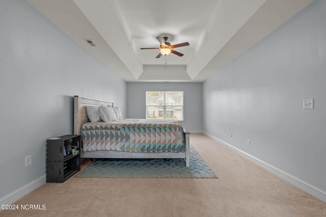 bedroom featuring a raised ceiling, carpet, and ceiling fan