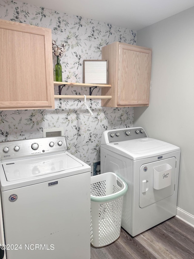 clothes washing area featuring dark wood-type flooring, cabinets, and washing machine and dryer