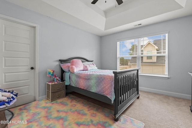 carpeted bedroom featuring ceiling fan and a raised ceiling