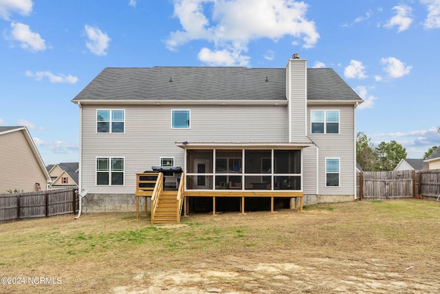 rear view of house featuring a sunroom and a lawn