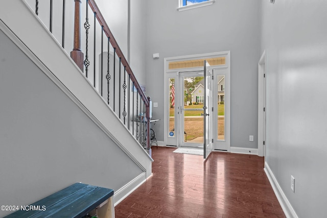 foyer entrance with dark wood-type flooring and a towering ceiling