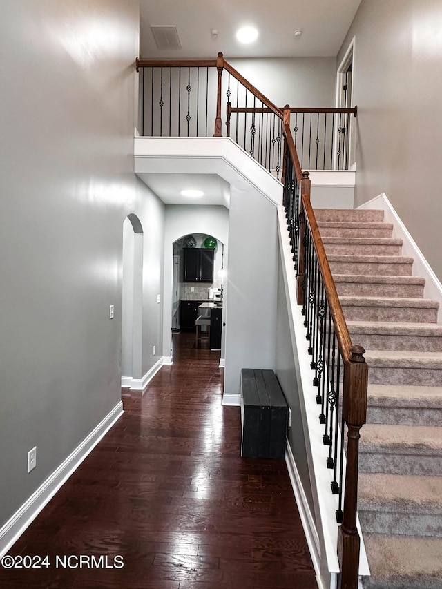 staircase with hardwood / wood-style flooring and a towering ceiling