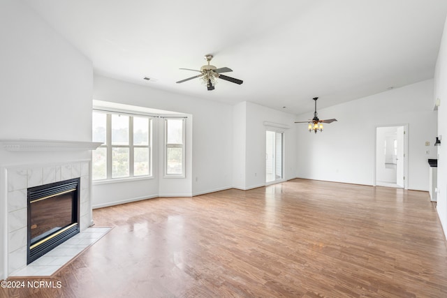 unfurnished living room with ceiling fan, light hardwood / wood-style flooring, lofted ceiling, and a tile fireplace