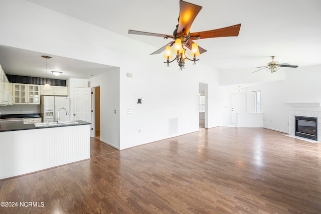 unfurnished living room featuring ceiling fan, sink, dark hardwood / wood-style flooring, and a tile fireplace