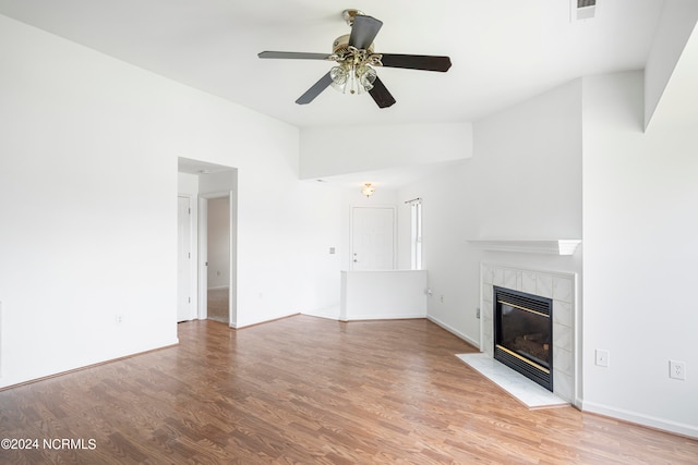 unfurnished living room with ceiling fan, light wood-type flooring, vaulted ceiling, and a tile fireplace