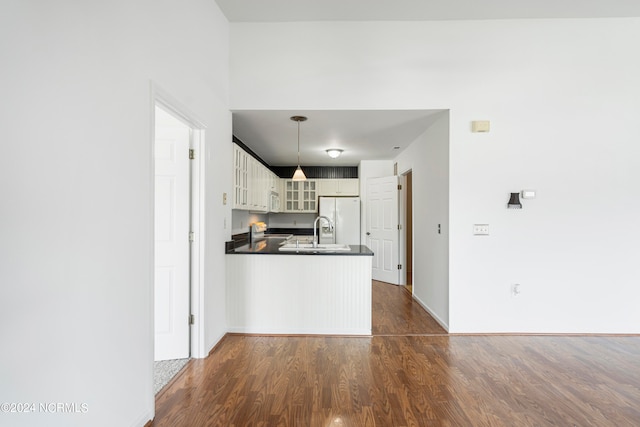 kitchen featuring pendant lighting, white appliances, kitchen peninsula, and dark hardwood / wood-style floors