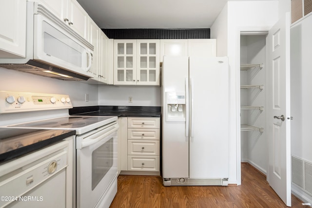 kitchen with white appliances, dark wood-type flooring, and white cabinets