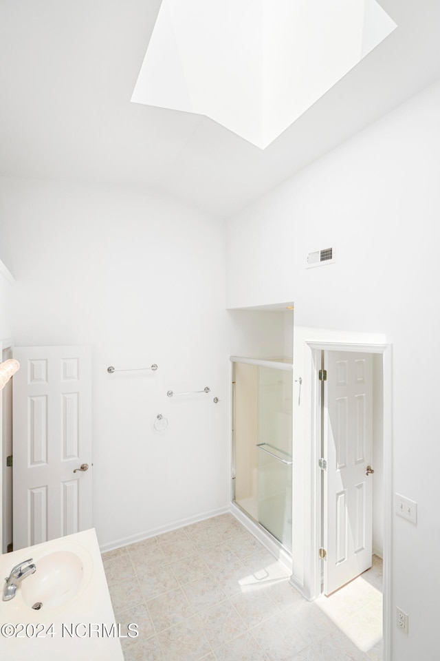 bathroom with a skylight, vanity, and a shower with door