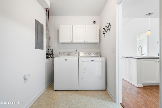 laundry room featuring electric panel, sink, washer and dryer, cabinets, and light hardwood / wood-style floors