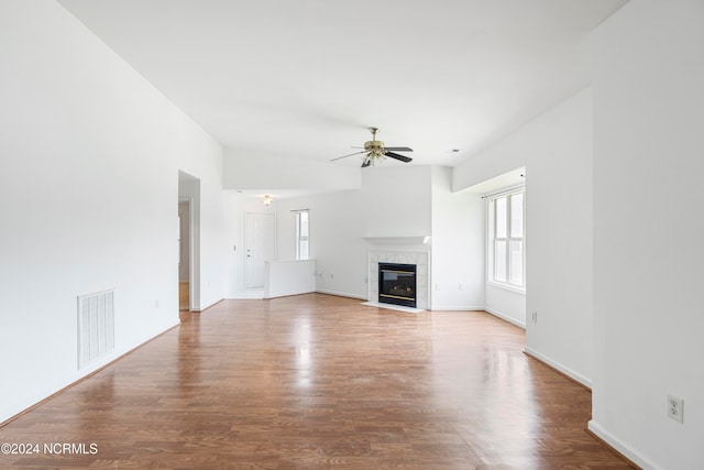 unfurnished living room with a tile fireplace, vaulted ceiling, ceiling fan, and hardwood / wood-style flooring