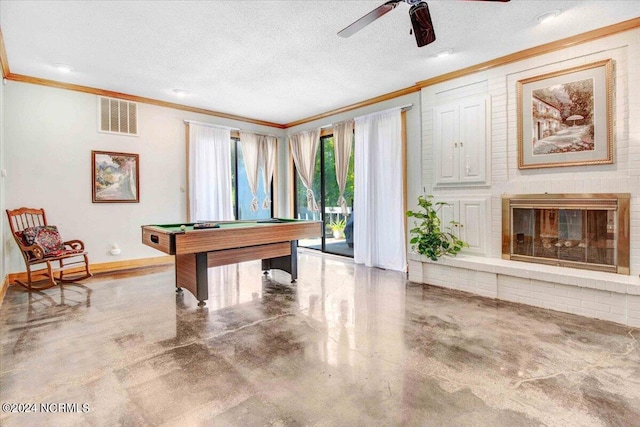 playroom featuring pool table, a textured ceiling, a brick fireplace, concrete floors, and ceiling fan