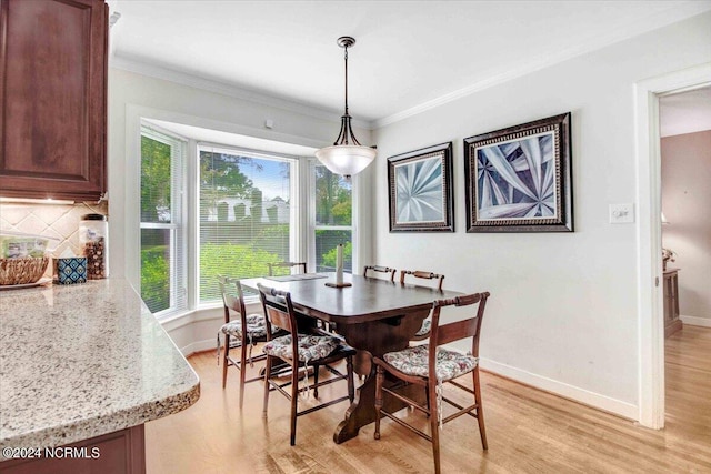 dining space featuring light hardwood / wood-style flooring and crown molding