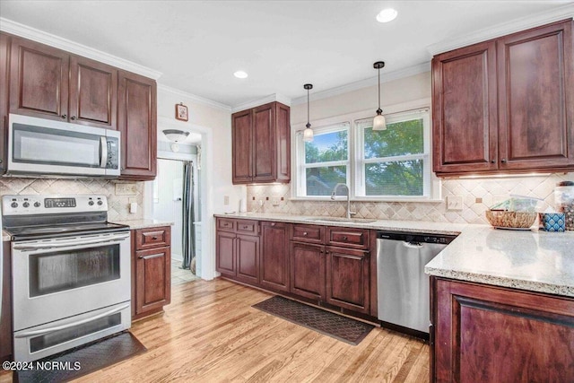 kitchen with light wood-type flooring, ornamental molding, sink, and stainless steel appliances