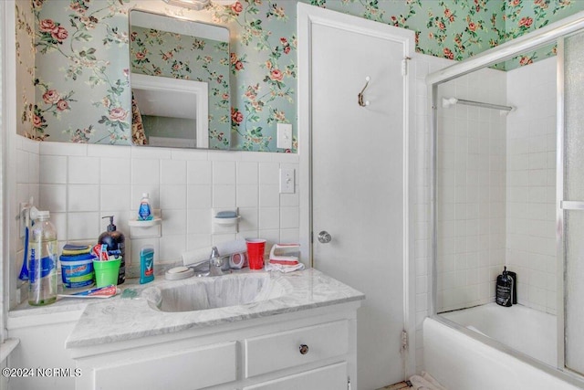 bathroom with tile walls, vanity, and combined bath / shower with glass door