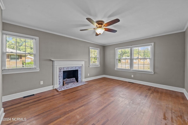 unfurnished living room featuring a brick fireplace, crown molding, hardwood / wood-style floors, and ceiling fan