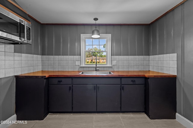 kitchen featuring sink, light tile patterned floors, gray cabinets, wood counters, and decorative light fixtures