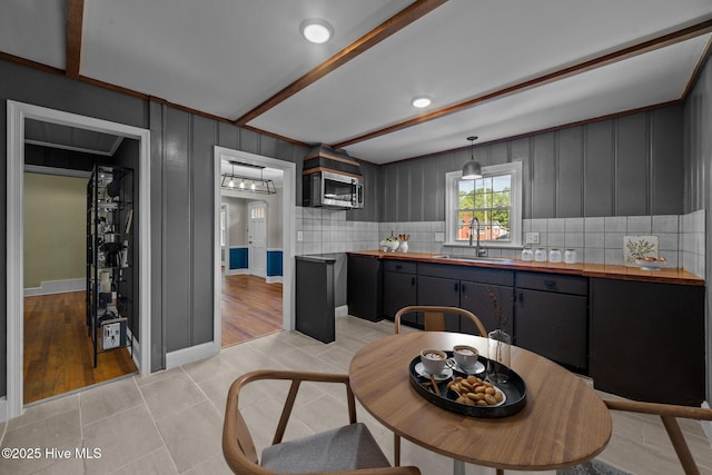 kitchen with butcher block countertops, decorative light fixtures, tasteful backsplash, sink, and light tile patterned floors