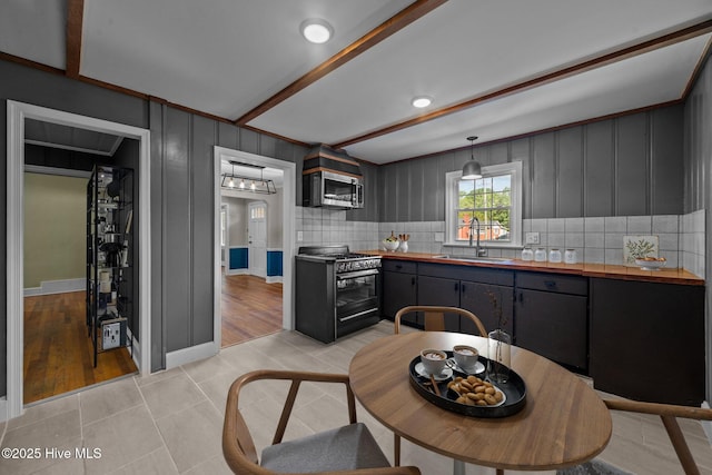 kitchen with stainless steel appliances, tasteful backsplash, butcher block countertops, and a sink