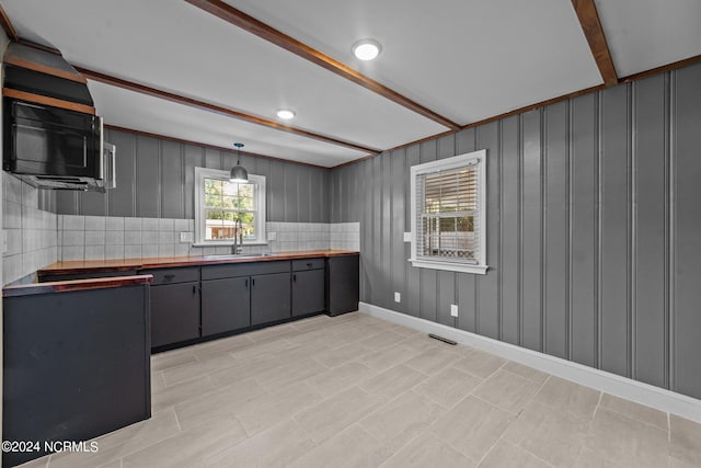 kitchen with pendant lighting, sink, gray cabinetry, wood counters, and decorative backsplash